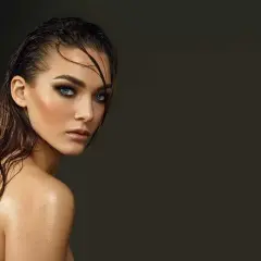 Jeune femme au regard intense, cheveux mouillés et peau luisante, un look aquatique saisissant.