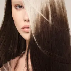 Une femme au regard intense, ses longs cheveux bruns contrastent avec des mèches blondes lumineuses. Un balayage inversé avant après spectaculaire.