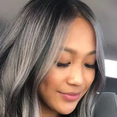 Une femme avec un balayage blanc sur cheveux noir, un style audacieux et moderne.