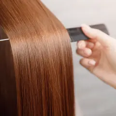 Une main peigne des cheveux longs et brillants, pour avoir les cheveux doux comme chez le coiffeur.