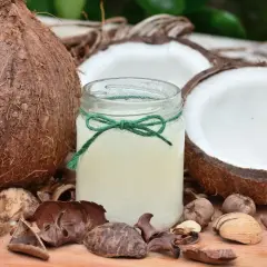 Un pot d'huile de coco, entouré de noix de coco coupées et de coques, un secret naturel pour des cheveux blancs éclatants.