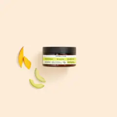 Un pot de beurre de soin cheveux Aroma-Zone, avec des tranches de mangue et d'avocat à côté.