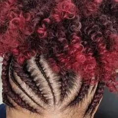 Tresses collées sur le cuir chevelu, contrastant avec une chevelure bouclée rouge et noire.