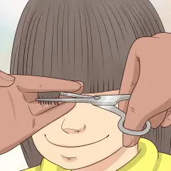 Une main tient une mèche de cheveux d'un enfant pour un couper cheveux enfant. Des ciseaux s'approchent pour la coupe.