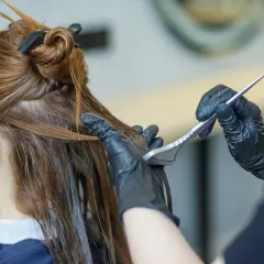 Application d'un soin capillaire sur des cheveux bruns avec une brosse.