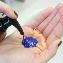 Une main pompe un shampoing bleu vif dans une paume ouverte. Le produit est prêt à être utilisé pour un avant-après spectaculaire.