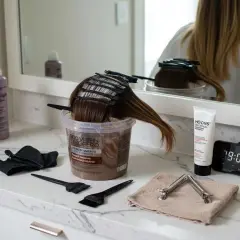 Préparation pour une coloration. On voit des produits capillaires, des pinceaux, des pinces et un mannequin de chevelure. Peut-on mélanger de l'oxydant 10 et 20 ?