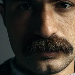 Gros plan sur le visage d'un homme, mettant en valeur un type de moustache broussailleuse et épaisse, aux reflets roux et bruns.