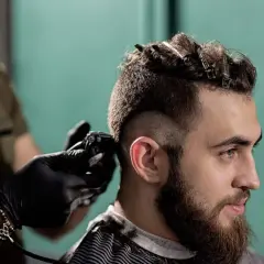 Un homme se fait couper les cheveux en coupe mohawk court par un coiffeur.