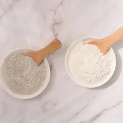 Deux bols de poudre, l'un gris et l'autre blanc, avec des cuillères en bois. L'argile blanche est parfaite pour les cheveux.