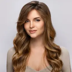Une jeune femme au regard captivant, ses longs cheveux méchés ondulés encadrant son visage.