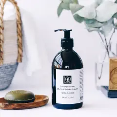 Savon liquide d'Alep pour les cheveux, avec un savon solide et une bouteille pompe. Un panier en osier est visible en arrière-plan.