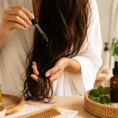 Application d'un sérum capillaire pour une recette bain d'huile cheveux pousse. Huiles naturelles et peigne en bois.