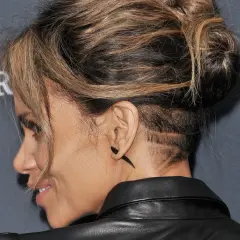 Une femme aux cheveux longs arbore un undercut audacieux avec des motifs rasés sur le côté.