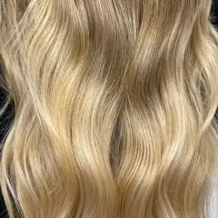 Chevelure blonde aux reflets dorés, un véritable révélateur de patine naturelle. Les ondulations douces encadrent le visage.