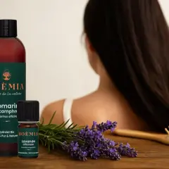 Flacon et petite fiole d'huile essentielle pousse cheveux, lavande et romarin, sur fond de cheveux longs.