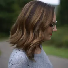Chevelure châtain avec reflets blonds, une femme porte des lunettes. Une idée pour comment cacher ses cheveux blancs quand on est blonde.
