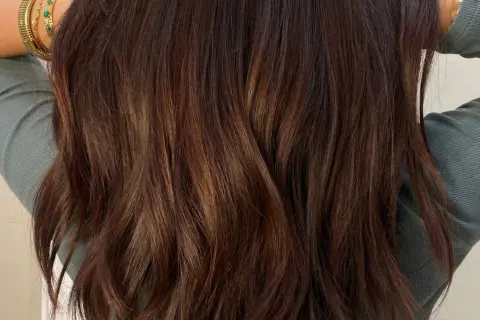 Cheveux bruns ondulés avec des reflets subtils. Une question se pose : comment enlever une patine cheveux pour retrouver une couleur naturelle ?