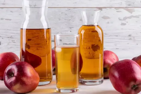 Pommes rouges et carafes de vinaigre de cidre, un ingrédient naturel pour savoir quel vinaigre pour les cheveux.