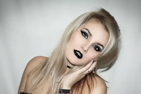 Une jeune femme avec une coiffure rock, maquillage intense et lèvres noires. Son regard est captivant.
