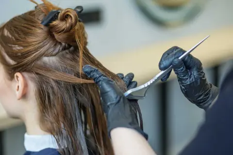 Application d'un soin capillaire sur des cheveux bruns avec une brosse.
