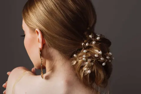 Coiffure soirée simple cheveux long, ornée d'une branche dorée avec perles et feuilles. Une touche d'élégance pour une occasion spéciale.