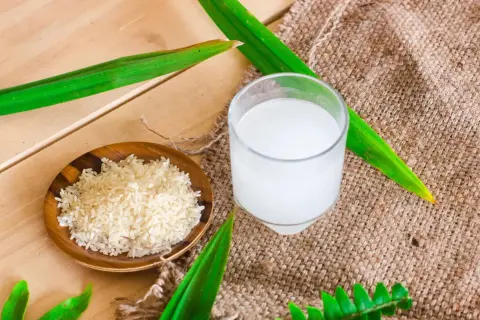 Un bol de riz cru et un verre d'eau de riz, parfaits pour des cheveux brillants.
