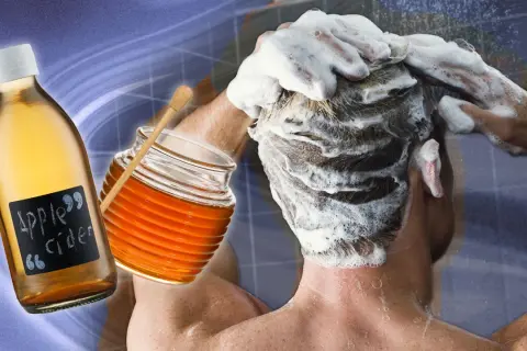 Une personne se lave les cheveux moussants, avec une bouteille de vinaigre de cidre et un pot de miel à proximité, pour éclaircir ses cheveux naturellement.