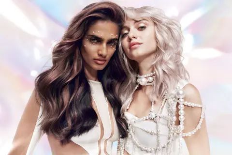 Deux femmes aux cheveux longs, ornées de perles. L'une a des reflets auburn, l'autre est platine. Un look d'activateur 6 ou 9.