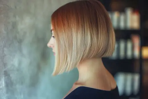 Profil d'une femme avec un carré très court derrière, dégradé du roux au blond.