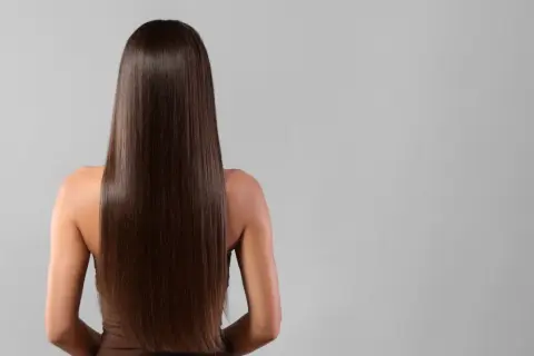 Vue arrière d'une femme aux longs cheveux bruns et brillants, résultat d'un brushing parfait.