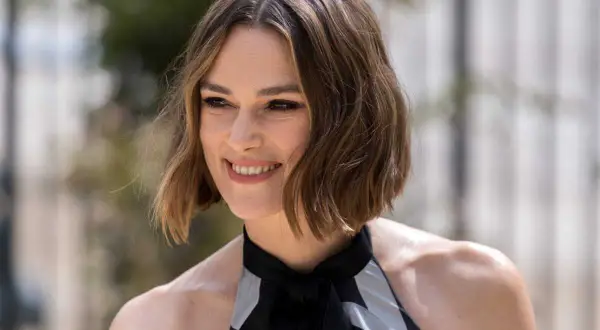 Une femme souriante, la cinquantaine, arbore une coupe dégradée qui donne du volume à ses cheveux fins et plats.