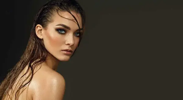 Jeune femme au regard intense, cheveux mouillés et peau luisante, un look aquatique saisissant.