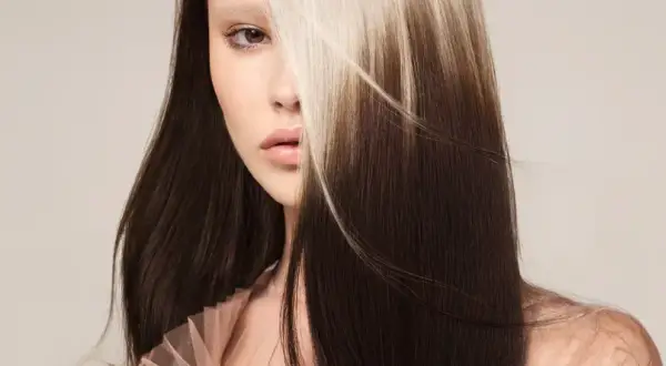 Une femme au regard intense, ses longs cheveux bruns contrastent avec des mèches blondes lumineuses. Un balayage inversé avant après spectaculaire.