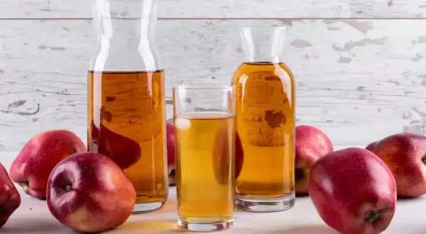 Pommes rouges et carafes de vinaigre de cidre, un ingrédient naturel pour savoir quel vinaigre pour les cheveux.