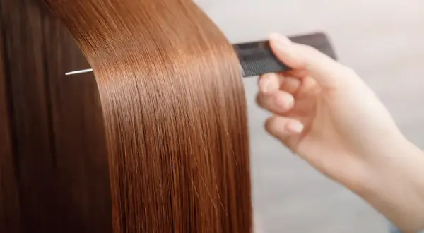 Une main peigne des cheveux longs et brillants, pour avoir les cheveux doux comme chez le coiffeur.