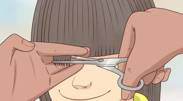 Une main tient une mèche de cheveux d'un enfant pour un couper cheveux enfant. Des ciseaux s'approchent pour la coupe.