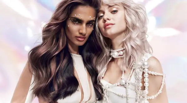 Deux femmes aux cheveux magnifiques, l'une brune avec des reflets roses, l'autre blonde platine. Un avant-après de la coloration Dialight Clear, sublimant leur éclat.
