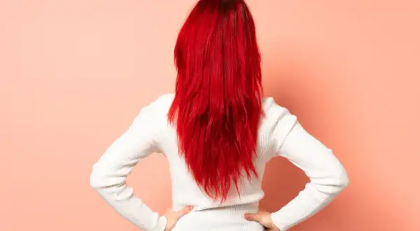 Vue arrière d'une femme aux cheveux rouge vif, cherchant comment enlever une coloration rouge naturellement.