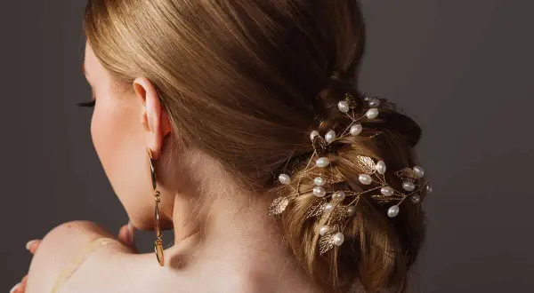 Coiffure soirée simple cheveux long, ornée d'une branche dorée avec perles et feuilles. Une touche d'élégance pour une occasion spéciale.