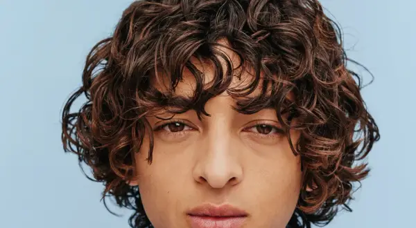 Gros plan sur un visage aux yeux marron et à la coiffure cheveux frisés bruns et volumineux.