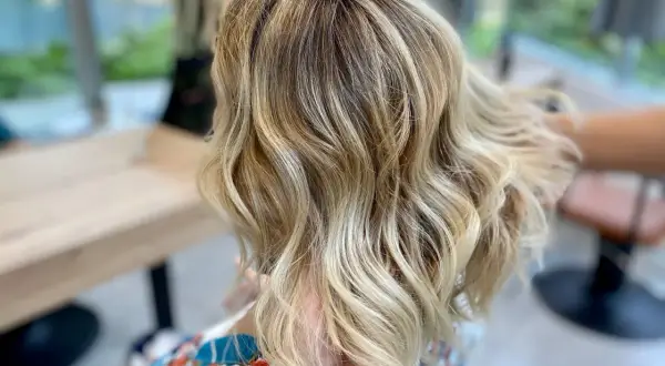 Chevelure blonde ondulée, aux reflets subtils, un bel effet ton sur ton.