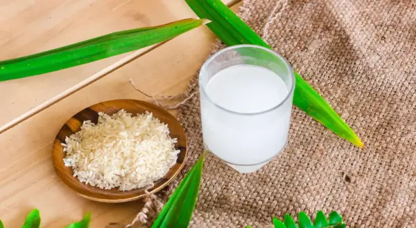 Un bol de riz cru et un verre d'eau de riz, parfaits pour des cheveux brillants.