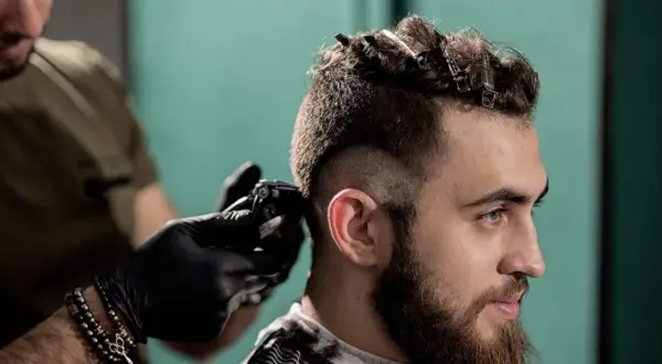 Un homme se fait couper les cheveux en coupe mohawk court par un coiffeur.