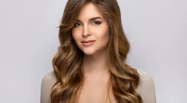 Une jeune femme au regard captivant, ses longs cheveux méchés ondulés encadrant son visage.