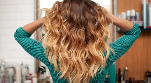 Cheveux longs ondulés avec un dégradé blond obtenu par décoloration cheveux maison.