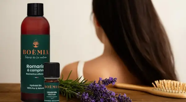 Flacon et petite fiole d'huile essentielle pousse cheveux, lavande et romarin, sur fond de cheveux longs.