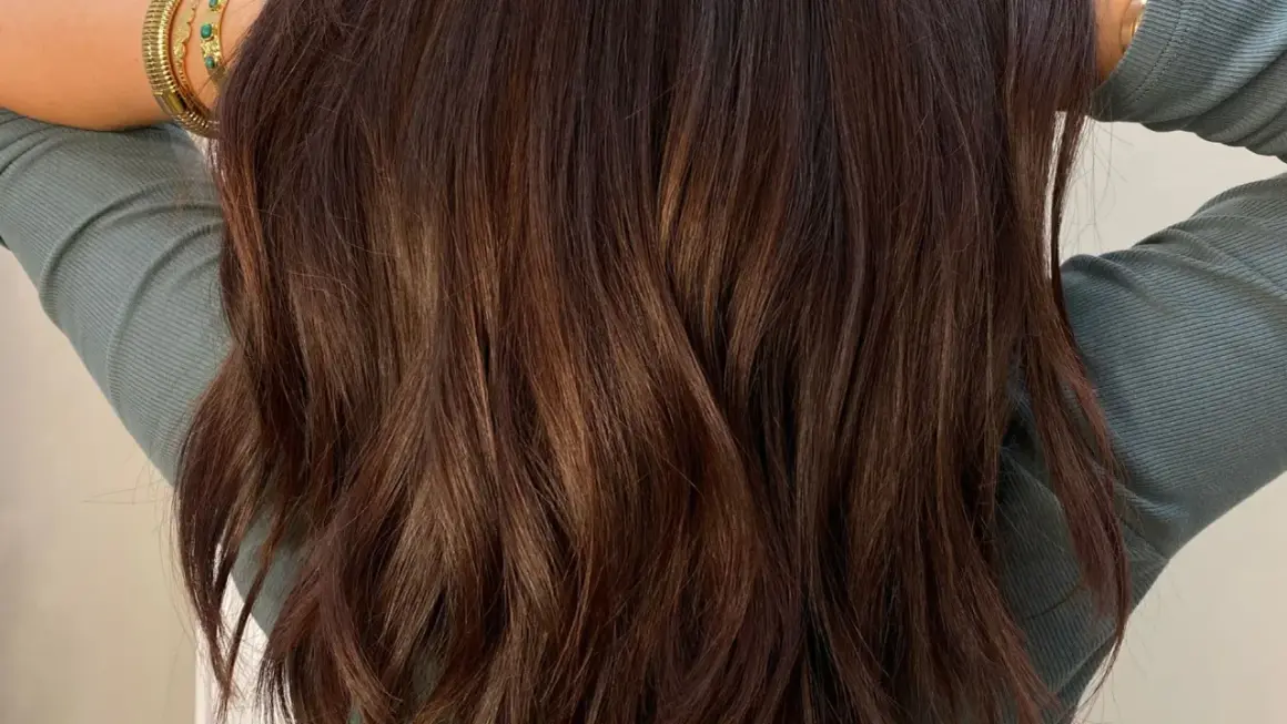 Cheveux bruns ondulés avec des reflets subtils. Une question se pose : comment enlever une patine cheveux pour retrouver une couleur naturelle ?