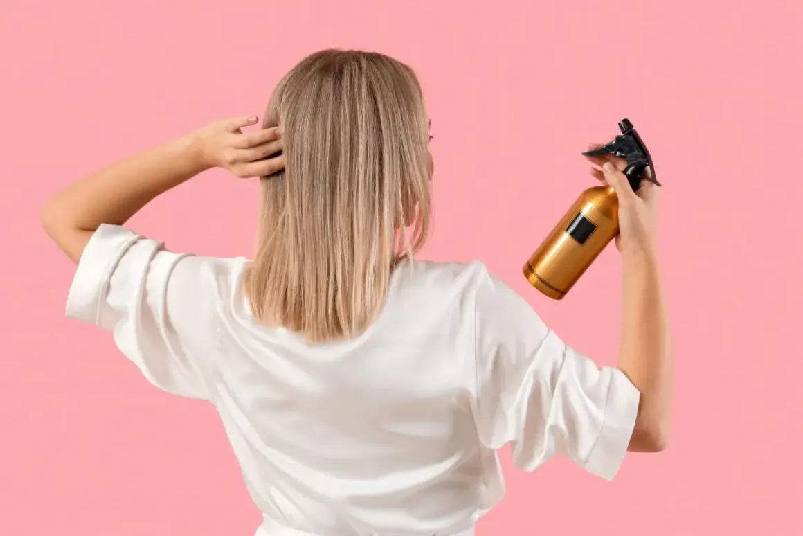 Une femme en peignoir blanc tient un flacon doré, prêt à utiliser du peroxyde d'hydrogène pour éclaircir ses cheveux blonds.