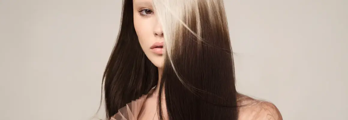 Une femme au regard intense, ses longs cheveux bruns contrastent avec des mèches blondes lumineuses. Un balayage inversé avant après spectaculaire.